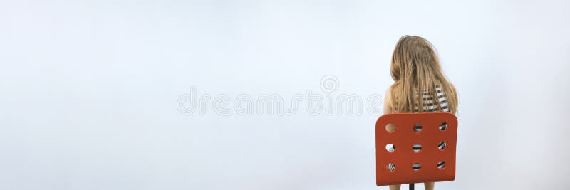 Girl sitting on red chair. Mental health concept. Teenager in depression. Kid at reception of psychologist. Sadness and bad mood. Background with copyspace. Stock photo.