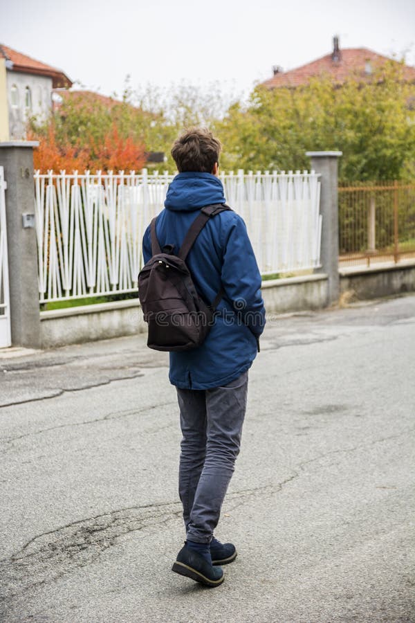Teenager, der allein in Straße mit Rucksack geht lizenzfreie stockfotos Teenager, der allein in Straße mit Rucksack geht lizenzfreie stockfotos