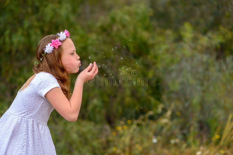 Teenager girl blowing dandelion.