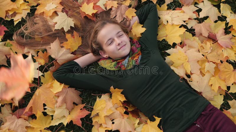 Teenager girl with falling autumn leaves