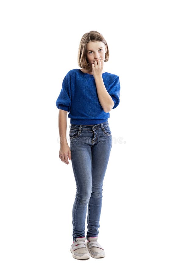 A teenager girl in jeans and a blue sweatshirt bites her nails. Full height. Isolated on a white background. Vertical