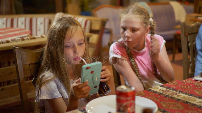 Teenager girl looking smartphone at dinning table. Young girl using mobile phone for watching video. Two girlfriends stock video