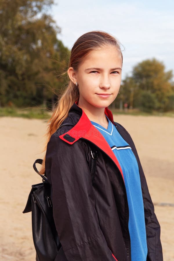 Teenager girl in a raincoat and backpack walk outdoors