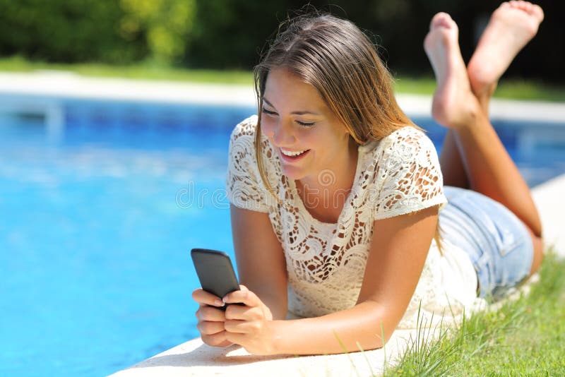 Teenager girl using a smart phone resting on a pool side