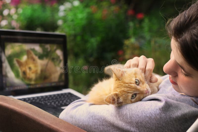 Dospievajúce dievča pracuje na retuše fotografií na notebook s červeným mačiatko na zelené kvetinové záhrade v lete pozadí.