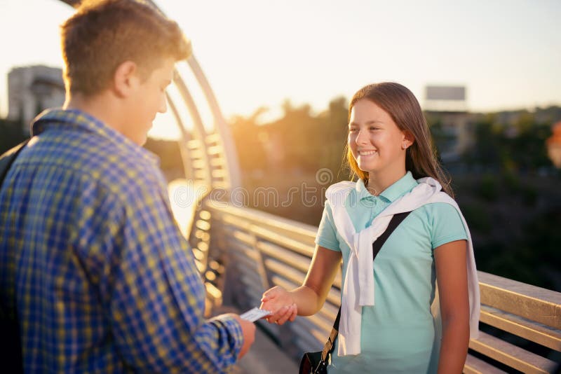 Teenager holding tickets for the cinema, give them to the girl stock image Teenager holding tickets for the cinema, give them to the girl stock image