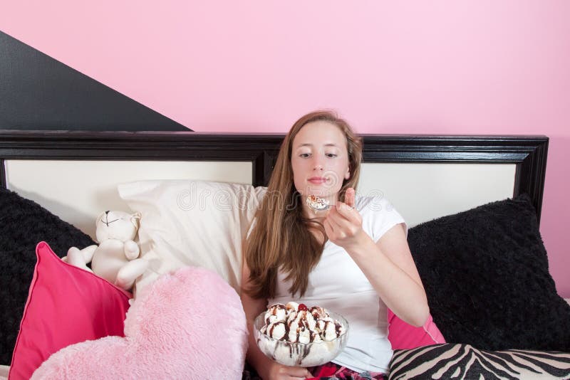 Unhappy Teen Eating Large Ice Cream Sundae In Her Room Stock Photo