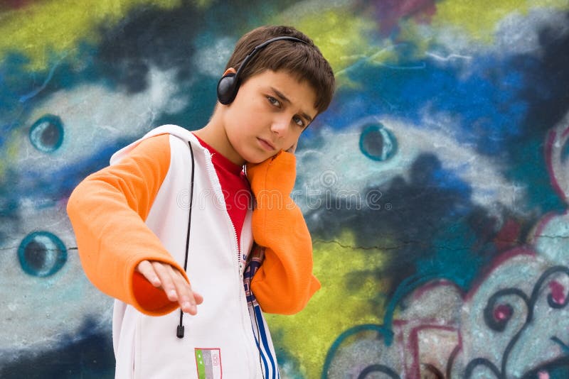 Teenager listening music against a graffiti wall