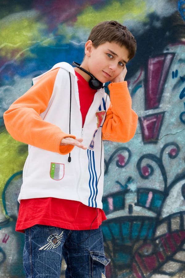 Teenager listening music against a graffiti wall