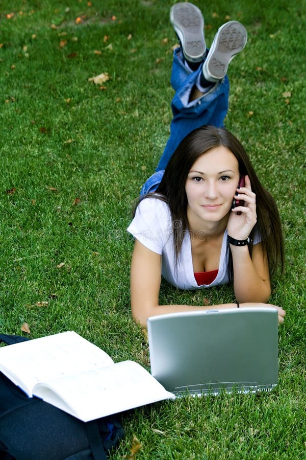 Teenager on the phone laying down on the grass