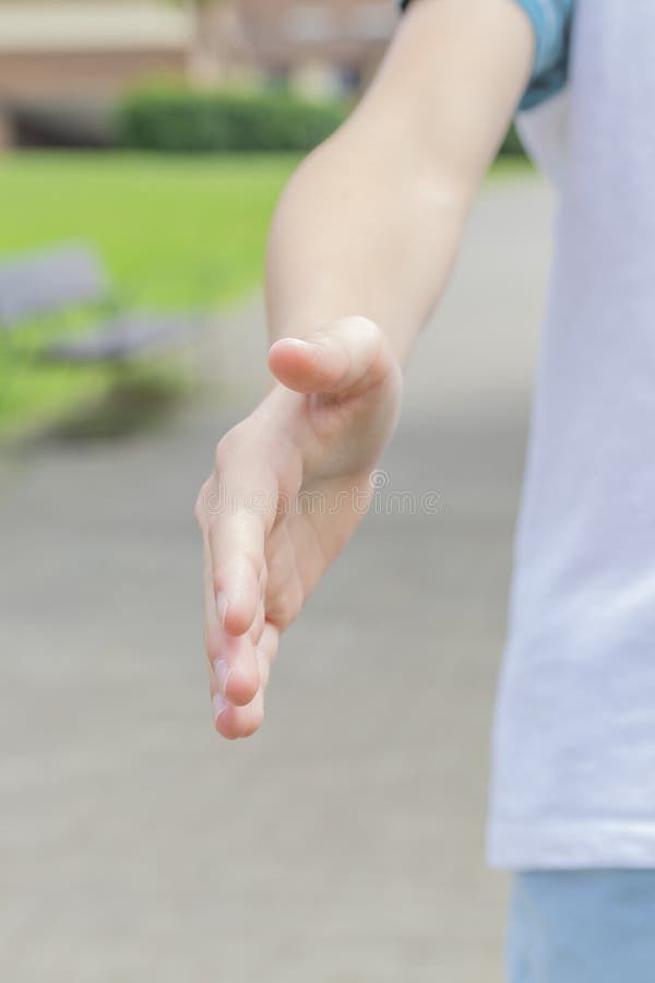 A teenager in sportswear extends his hand for a handshake and invites for a jog in the park royalty free stock photography A teenager in sportswear extends his hand for a handshake and invites for a jog in the park royalty free stock photography