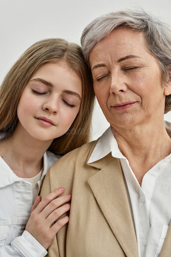 Teenagermädchen umarmt Seniorin im Studio stockbild