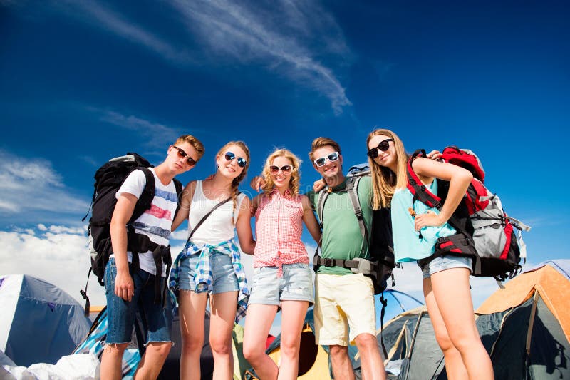 Teenageři před stany s batohy, letní festival