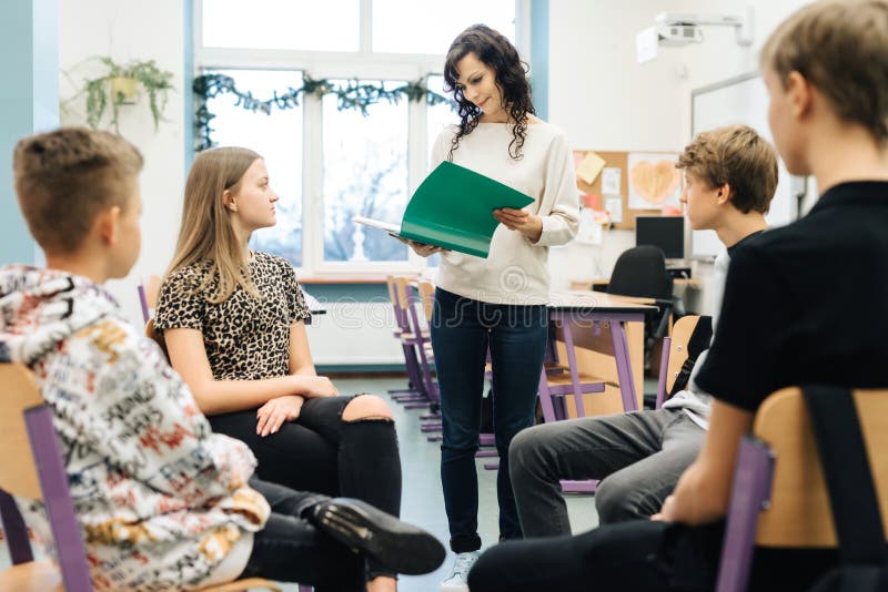 Teenagers sitting in a circle in front of them facing the nurse with a green notebook