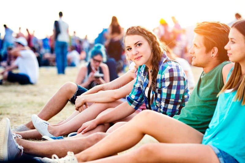 Tínedžeri na letnom hudobnom festivale, sediaci na zemi