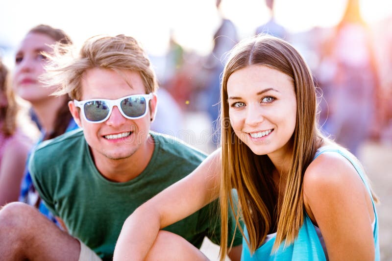 Teenage boy and girl enjoying a summer music festival, sitting on the ground. Teenage boy and girl enjoying a summer music festival, sitting on the ground