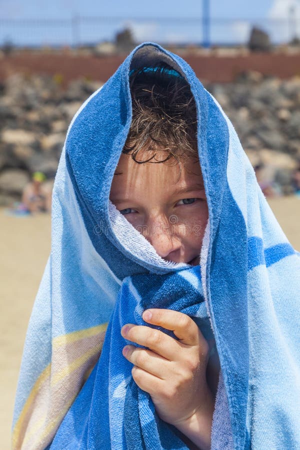 Teenboy with towel over his head at the beach