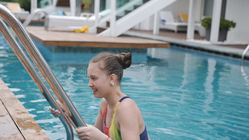 Teenmädchen in einem Badeanzug kommt runter oder die Treppe zum Pool