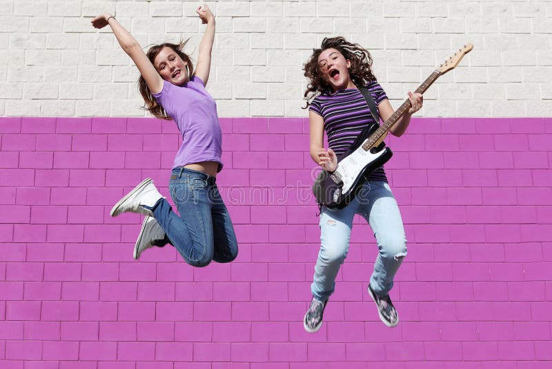 Teens playing guitar jumping