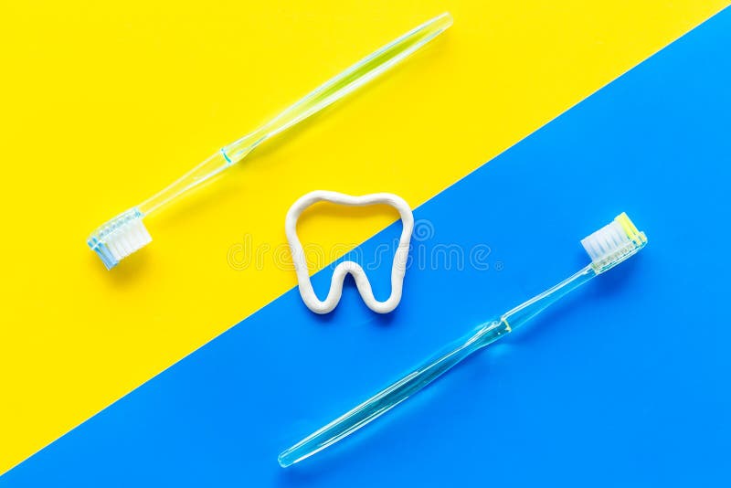 Teeth-Bürst-Konzept Zahnseide mit Zahnpasta in der Nähe von Zahnbürsten auf der gelben und blauen Hintergrundansicht stockfotografie