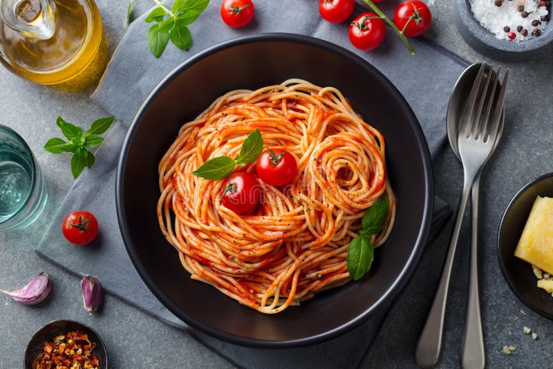 Teigwaren, Spaghettis mit Tomatensauce in der schwarzen Schüssel auf grauem Steinhintergrund Beschneidungspfad eingeschlossen stockbild Teigwaren, Spaghettis mit Tomatensauce in der schwarzen Schüssel auf grauem Steinhintergrund Beschneidungspfad eingeschlossen stockbild