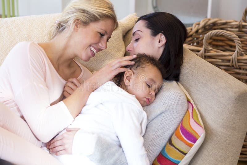 Same sex female couple lying down with their baby son. Same sex female couple lying down with their baby son