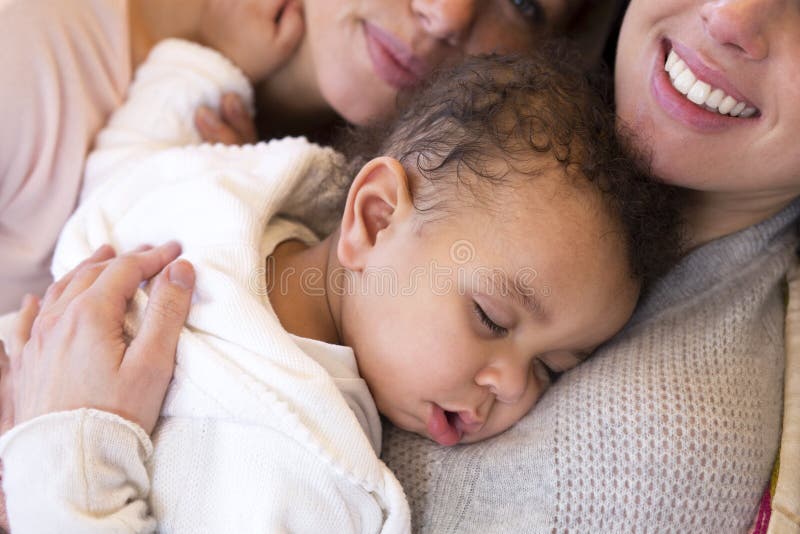 Same sex female couple lying down with their baby son. Same sex female couple lying down with their baby son