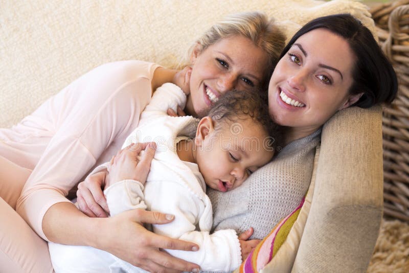 Same sex female couple lying down with their baby son. Same sex female couple lying down with their baby son