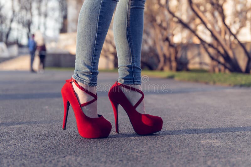 Tejanos Que Llevan De La Mujer Y Zapatos Rojos Del Tacón Alto Los Tacones Altos De La Ropa De Mujer Se Colocan En El Camino P Foto de archivo - Imagen