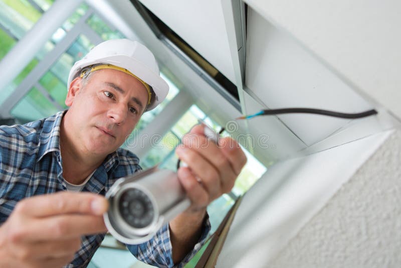 Teknikerarbetare som installerar den videopd bevakningkameran på väggen royaltyfria bilder Teknikerarbetare som installerar den videopd bevakningkameran på väggen royaltyfria bilder
