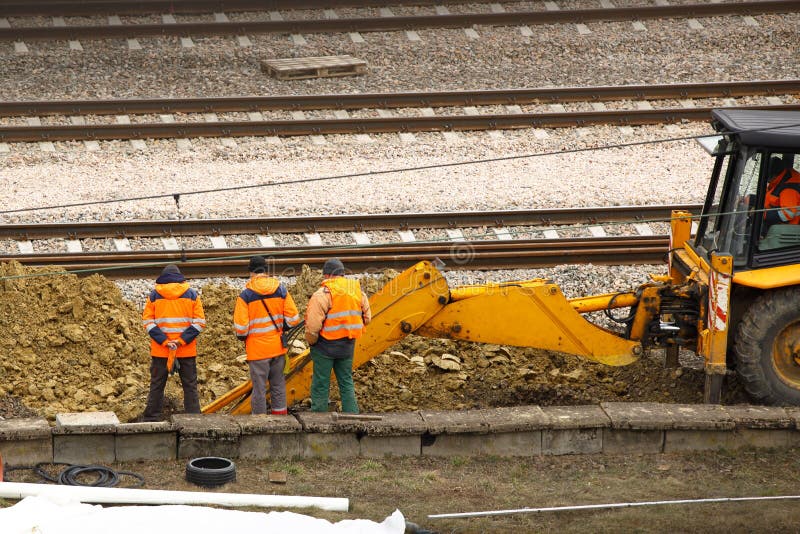 Teknikerer och järnväg arbetare reparerar spåret genom att använda en grävskopa Infrastruktur av transportkommunikationsknutpunkt royaltyfri fotografi Teknikerer och järnväg arbetare reparerar spåret genom att använda en grävskopa Infrastruktur av transportkommunikationsknutpunkt royaltyfri fotografi