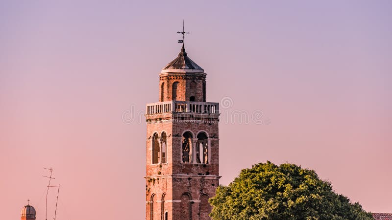Teknologisk kontrast över åldrigt klockatorn med kors- och telekommunikationantenner, Venedig, Italien, sommartid royaltyfria foton Teknologisk kontrast över åldrigt klockatorn med kors- och telekommunikationantenner, Venedig, Italien, sommartid royaltyfria foton