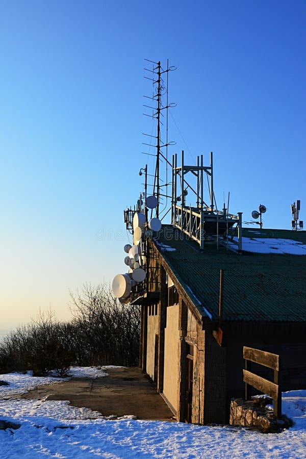 Telekomunikační a mikrovlnné antény a paraboly instalované na horní stanici aricable. Večerní slunce a modrá obloha během