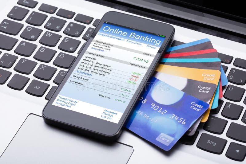 Close-up Of Mobilephone With Online Banking App And Credit Cards On Computer Keyboard. Close-up Of Mobilephone With Online Banking App And Credit Cards On Computer Keyboard