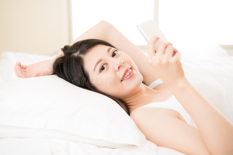 Telefon-Lesetextnachricht des entspannten asiatischen Frauengebrauches intelligente stockbild Telefon-Lesetextnachricht des entspannten asiatischen Frauengebrauches intelligente stockbild