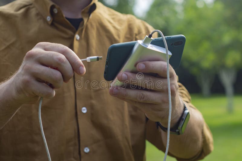 Telefon med laddare utomhus, mobil teknik i naturen royaltyfri foto