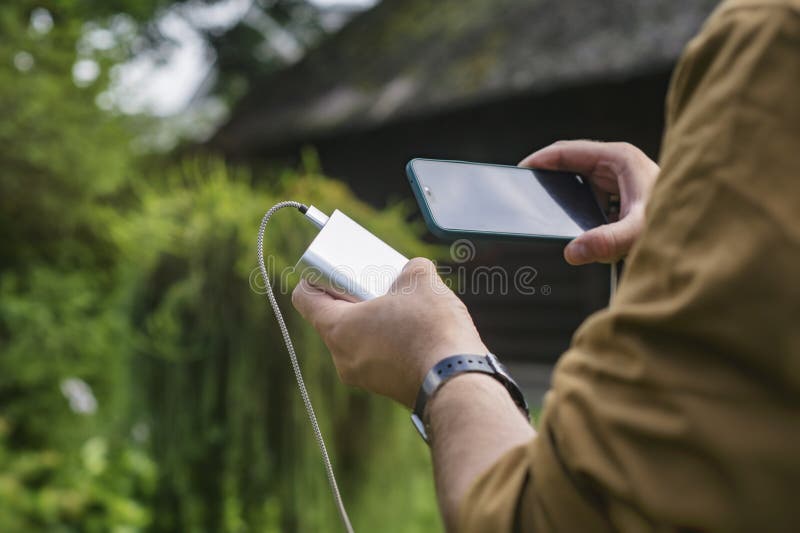 Telefon med laddare utomhus, mobil teknik i naturen royaltyfri fotografi