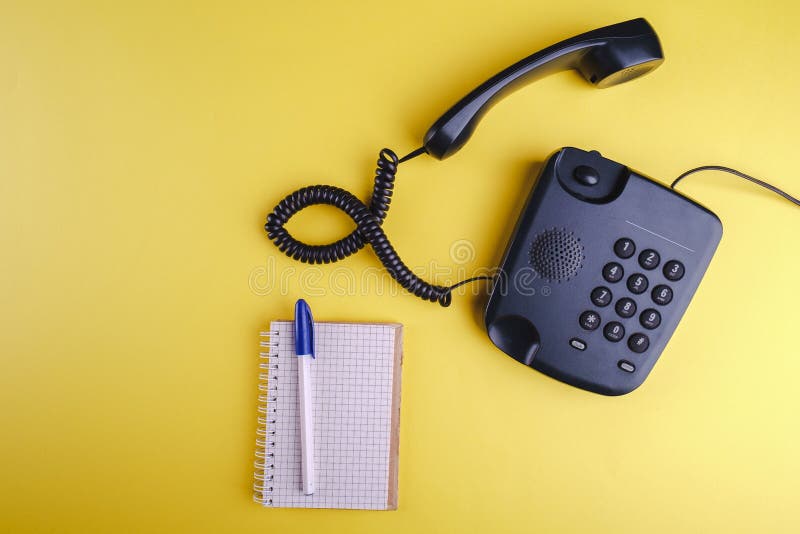 Telefone antiquado backgroundOld amarelo no telefone formado no fundo amarelo com caderno e a pena vazios foto de stock royalty free Telefone antiquado backgroundOld amarelo no telefone formado no fundo amarelo com caderno e a pena vazios foto de stock royalty free