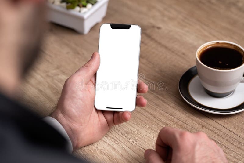 Telefone celular da terra arrendada da mão do homem na mesa no escritório foto de stock Telefone celular da terra arrendada da mão do homem na mesa no escritório foto de stock