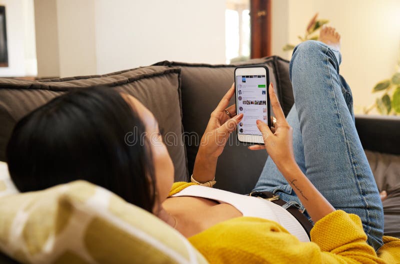 Jovem mulher sorrindo e rindo enquanto envia mensagens de texto em um  telefone em casa mulher alegre conversando com seus amigos com aplicativos  rolando mídias sociais e assistindo memes engraçados da internet enquanto  relaxa em um sofá