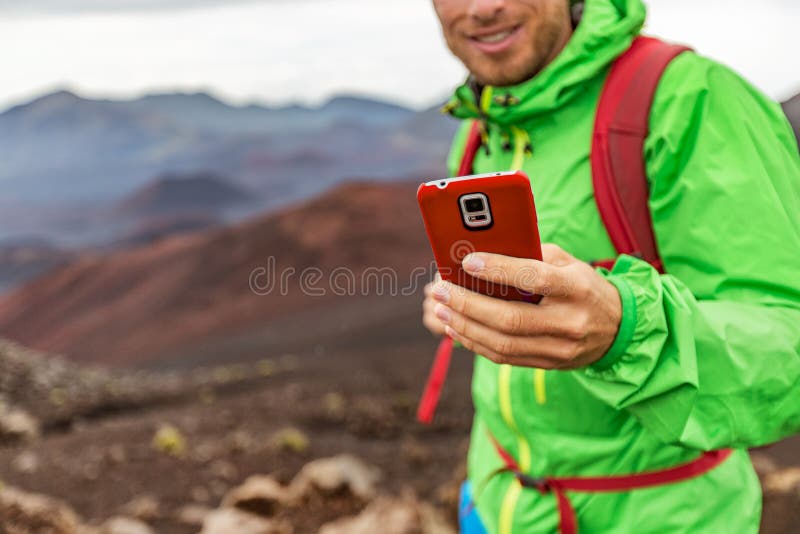 Telefonmann, der während der Wanderungswanderung im Vulkanberg simst Jugendlicher auf Reiselebensstil unter Verwendung seines Sma lizenzfreies stockbild