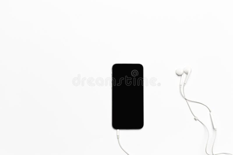 Telefono cellulare con le cuffie bianche isolate su bianco immagini stock