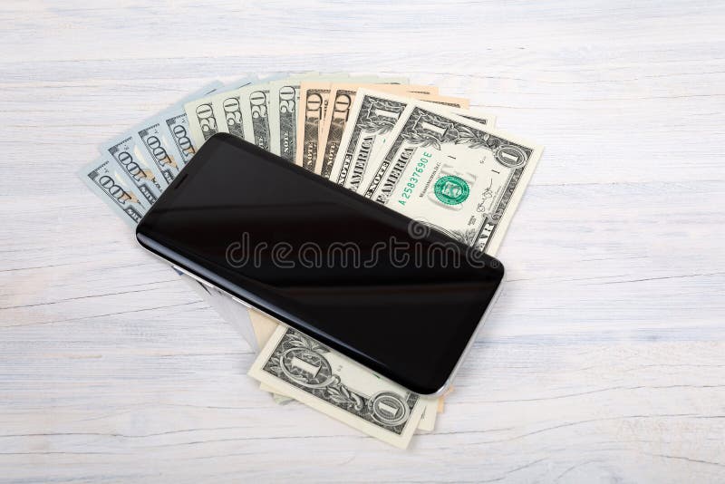 Telefono cellulare e soldi americani del dollaro su bianco fotografie stock libere da diritti Telefono cellulare e soldi americani del dollaro su bianco fotografie stock libere da diritti