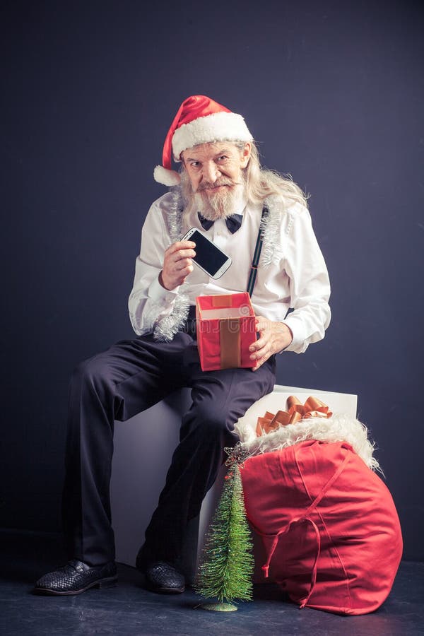 Telefono cellulare felice della tenuta di Santa dell'ufficio come regalo di natale fotografia stock libera da diritti Telefono cellulare felice della tenuta di Santa dell'ufficio come regalo di natale fotografia stock libera da diritti