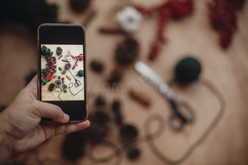 Telefono della tenuta della mano e foto di presa della corona rustica f di natale fotografie stock Telefono della tenuta della mano e foto di presa della corona rustica f di natale fotografie stock