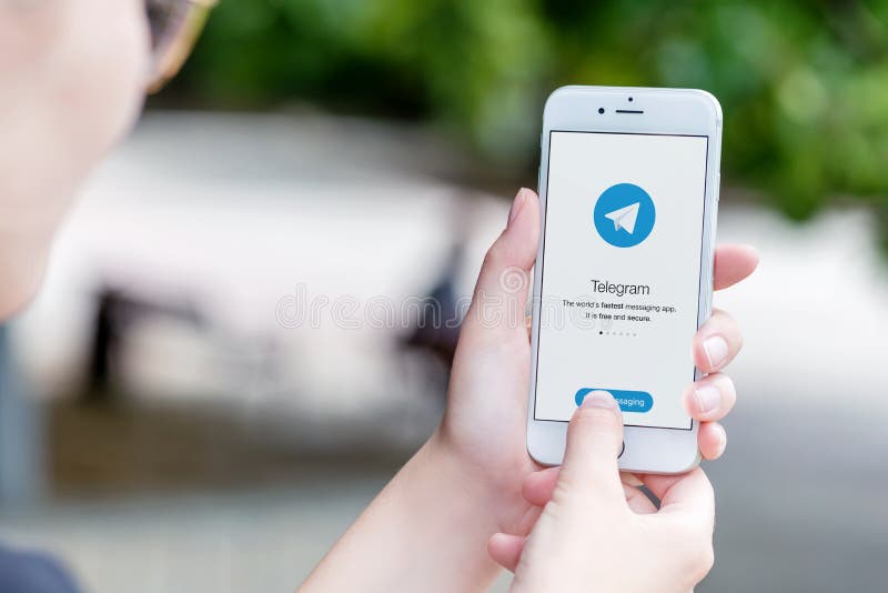 Telegram messenger on Apple iPhone in female hands over the shoulder view