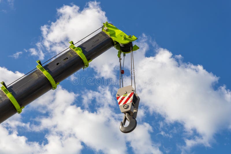 Telescopic boom of a mobile crane with a hook against a cloudy sky. Construction and repair equipment for lifting loads