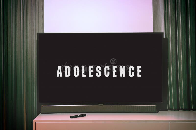Television screen showing the title Adolescence from a Netflix series. A remote control is placed on the cabinet below royalty free stock photo