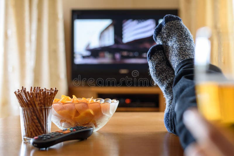 Television, TV som håller ögonen på (filmen) med fot på tabellen, och enorm amou arkivfoton Television, TV som håller ögonen på (filmen) med fot på tabellen, och enorm amou arkivfoton