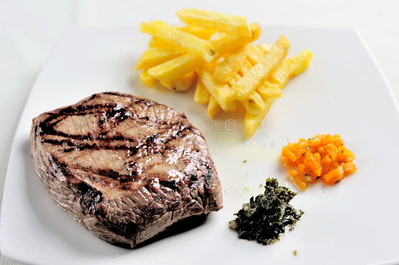 Teller mit gegrilltem Fleisch Fleisch, Pommes-Frites begleitet von chimichurri Soße stockbild Teller mit gegrilltem Fleisch Fleisch, Pommes-Frites begleitet von chimichurri Soße stockbild